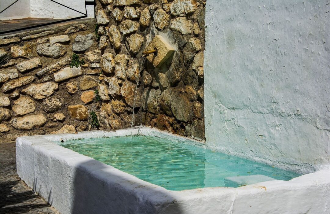 Bassin de fontaine en pierre, alimenté par un ancien robinet