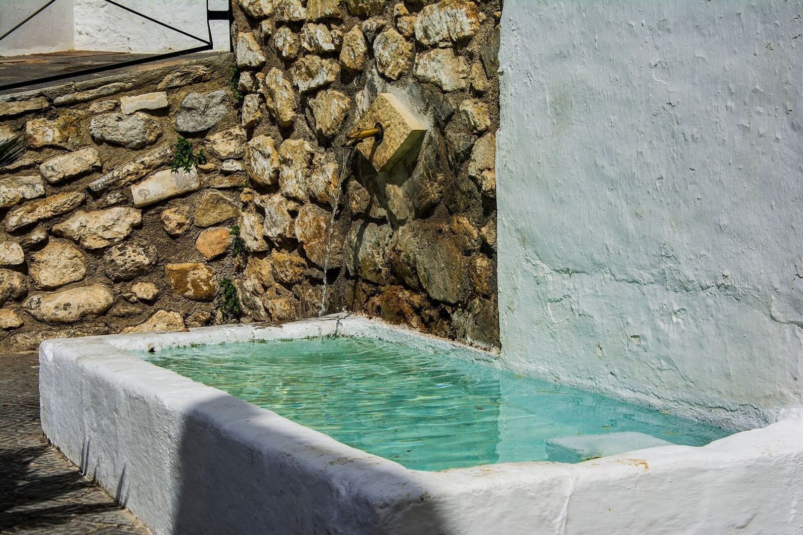 Bassin de fontaine en pierre, alimenté par un ancien robinet
